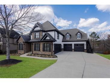Stunning two-story home with a three-car garage, stone accents, and lush green lawn at 2077 Towne Mill Ave, Canton, GA 30114