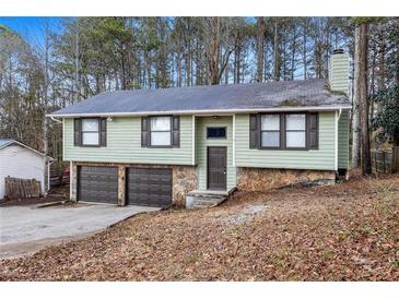 Charming two-story home featuring a stone foundation and a two-car garage, nestled among mature trees at 7316 Caribou Trl, Riverdale, GA 30296