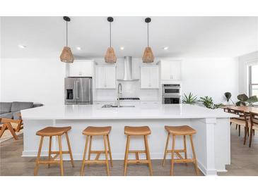 Bright white kitchen with stainless steel appliances, large island, and modern pendant lighting at 1312 Stanley Park Dr, Decatur, GA 30033