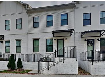 Charming townhome featuring a painted brick facade, a covered entry, and manicured landscaping at 2461 Sycamore Nw Rd, Atlanta, GA 30318