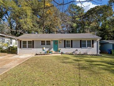 Charming single-story home featuring a brick facade, teal door, and well-maintained lawn with mature trees at 1824 Evans Sw Dr, Atlanta, GA 30310