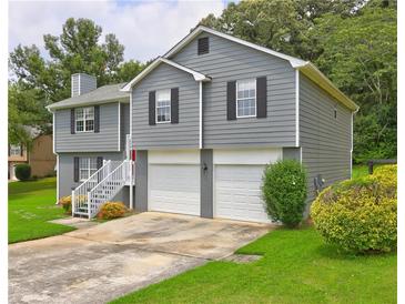 Charming two-story home featuring a two-car garage, gray siding, and a well-maintained front yard with mature trees at 4090 Mark Todd Ct, Hoschton, GA 30548
