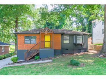 Charming home featuring a colorful front door, wood accents, and a well-maintained lawn with mature trees at 1251 Richland Sw Rd, Atlanta, GA 30310
