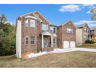 Two-story brick home featuring a two-car garage, a manicured lawn, and mature trees at 2725 Palmview Sw Ct, Atlanta, GA 30331