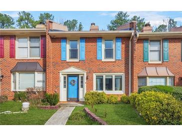 Charming brick townhome featuring colorful shutters, a bright blue door with wreath, and manicured front yard at 6105 Queen Anne Ct, Norcross, GA 30093