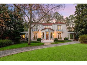 Elegant two-story white home with a red tile roof, manicured lawn, and beautiful landscaping at 401 Peachtree Battle Nw Ave, Atlanta, GA 30305