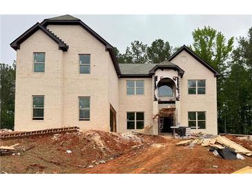 An unfinished two-story home with a brick facade and dark trim, set on a lot with trees in the background at 206 Lotus Ln, Covington, GA 30016