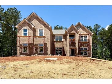 New construction of a two-story brick home featuring large windows and a classic architectural style in a wooded setting at 218 Lotus Ln, Covington, GA 30016