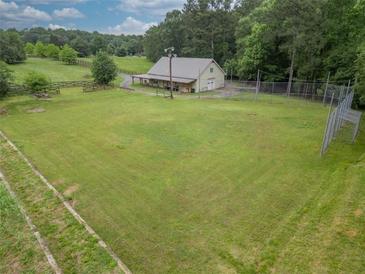 Expansive grassy field with a charming building and wooden fence, surrounded by lush trees at 3285 Kelly Glen Ct, Dacula, GA 30019