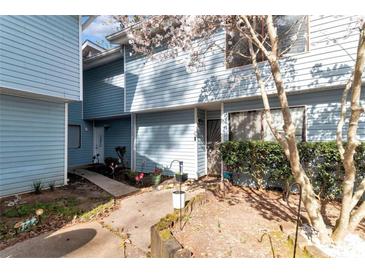 Charming townhome featuring blue siding, blooming tree and walkway leading to the front door at 922 Lakewood Ln, Jonesboro, GA 30238