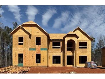 Two-story new construction home showcasing the facade with visible framing and arched entryway against a bright, partly cloudy sky at 3118 Old Covington Hwy, Covington, GA 30014