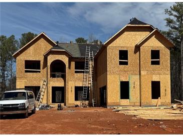 Two story new construction featuring an arched doorway and ladder to the roof at 3128 Old Covington Hwy, Covington, GA 30014