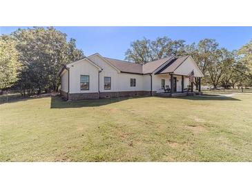 Charming single-story home with white siding, black trim and lovely front porch on a large lawn at 2418 Claude Brewer Rd, Loganville, GA 30052