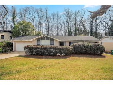 Ranch home with a brick facade, manicured shrubs, a one-car garage and a well-maintained front lawn at 4063 Elmscourt Dr, Stone Mountain, GA 30083