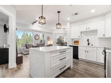 Bright kitchen featuring white cabinets, subway tile backsplash, and a center island with marble countertop at 200 River Vista Dr # 502, Atlanta, GA 30339