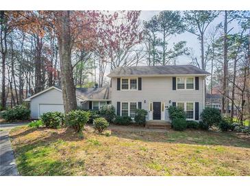 Charming two-story home featuring gray siding, black shutters, and a well-maintained front yard with mature trees at 4641 Waterford Ct, Atlanta, GA 30338