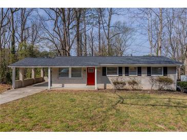 Charming single-story home with a white brick exterior, covered carport, well-maintained lawn, and bright red front door at 3465 Tulip Dr, Decatur, GA 30032