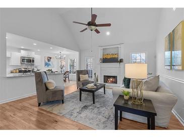 Bright living room with hardwood floors, ceiling fan, and a cozy fireplace at 7065 Walnut Mill Ct, Cumming, GA 30040