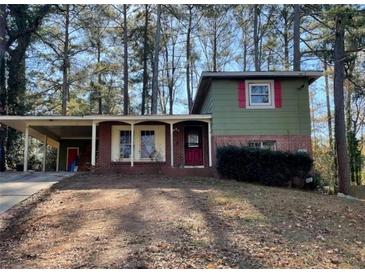 View of a two-story home with brick and wood facade, covered parking, and a yard at 2836 Oldknow Dr, Atlanta, GA 30318