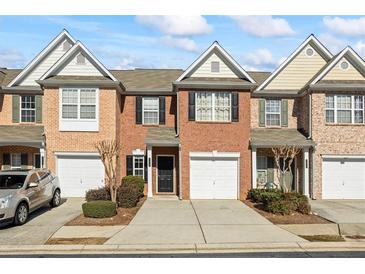 Traditional red brick townhome featuring a single-car garage and a well-maintained front yard with manicured shrubbery at 3815 Pleasant Oaks Dr, Lawrenceville, GA 30044