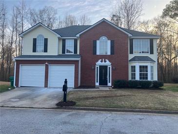 Two-story home featuring brick and siding, a two-car garage, and manicured landscaping at 6023 Kingston Wood Way, Lithonia, GA 30038