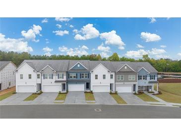 Charming townhomes feature varied colors, attached garages, and professional landscaping against a blue sky at 1186 Westhampton Way # 134, Villa Rica, GA 30180