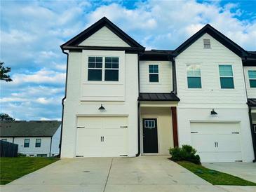 Charming townhome featuring a two-car garage, black roofline and a well-maintained front lawn at 124 Auburn Run Ln, Auburn, GA 30011