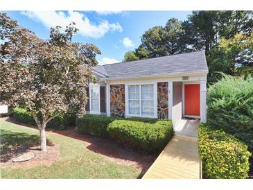 Charming one-story home with stone accents, vibrant orange door, accessible wooden ramp, and manicured landscaping at 361 Oak Harbor Trl, Marietta, GA 30066