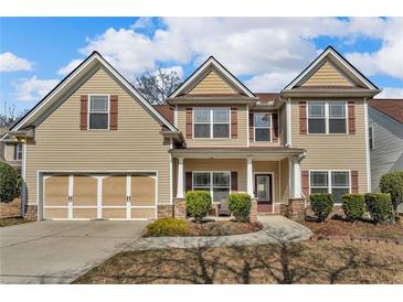 Charming two-story home featuring tan siding, complementary shutters, and a manicured front yard for great curb appeal at 1531 Autumn Wood Trl, Buford, GA 30518