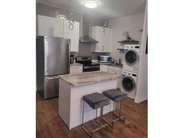 Charming kitchen featuring stainless steel appliances, an island with seating, and a stacked washer/dryer at 3060 Pharr Court North Nw # 306, Atlanta, GA 30305