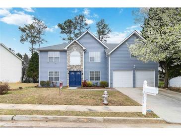 Charming two-story home featuring a blue facade, stone accents, attached garages, and a well-maintained lawn at 6274 Katelyn Park, Lithonia, GA 30058