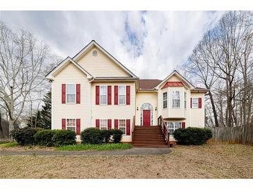 Charming two-story home featuring red shutters, yellow siding, a front porch, and manicured landscaping at 4020 F A A Rd, Cumming, GA 30041