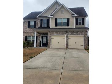 Charming two-story home featuring a brick and siding facade, a two-car garage, and a well-maintained lawn at 2436 Planters Mill Way, Conyers, GA 30012