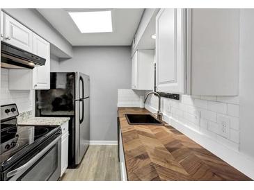A modern kitchen featuring white cabinets, stainless steel appliances, and a wood countertop with a black sink at 117 Lablanc Nw Way, Atlanta, GA 30327