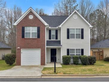 Charming two-story home featuring brick and siding accents, with a one-car garage and well-maintained landscaping at 7006 Mahonia Pl, Lithonia, GA 30038