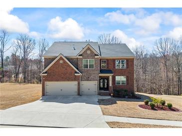 Inviting brick two-story home with an attached two-car garage, manicured lawn, and lush landscaping at 3316 Quarter Horse Ln, Conyers, GA 30013