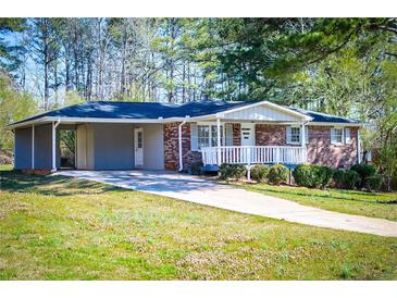 Charming single-story brick home with a covered carport, front porch, and well-maintained landscaping at 5042 Central Church Rd, Douglasville, GA 30135