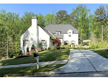 Charming two-story white home featuring a well-manicured lawn, a long driveway and a chimney at 5210 Timber S Trl, Sandy Springs, GA 30342