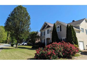 Charming two-story home with lush front lawn, mature tree, and vibrant flowering bushes on a sunny day at 1919 Barrett Knoll Nw Cir, Kennesaw, GA 30152