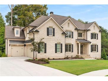 Charming two-story brick home with black shutters, a manicured lawn, and a three car attached garage at 4827 Basingstoke Dr, Suwanee, GA 30024