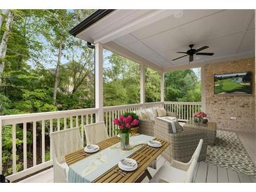Covered outdoor patio featuring comfortable seating, dining area, ceiling fan, and view of lush greenery at 4827 Basingstoke Dr, Suwanee, GA 30024