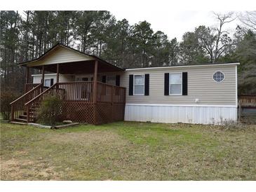 Charming home featuring a covered porch, wood stairs, and neutral siding, nestled among tall trees at 59 Pine Ridge Ln, White, GA 30184