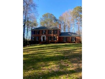 Charming brick home with a lush lawn, surrounded by mature trees on a sunny day at 1095 Willow Bnd, Roswell, GA 30075