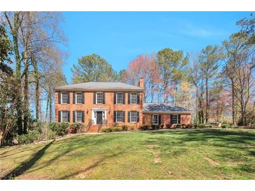 Traditional brick home with a manicured lawn and mature trees showcasing curb appeal at 1095 Willow Bnd, Roswell, GA 30075