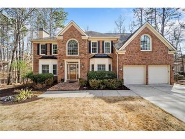 Charming two-story brick home with a well-manicured lawn, trimmed bushes, and a two-car garage, complemented by mature trees at 1904 Rosewood Ln, Woodstock, GA 30189