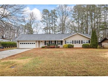 Charming single-story home featuring a well-maintained lawn, inviting front porch, and attached two car garage at 334 Nancy Sw Ct, Lilburn, GA 30047