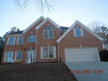 Charming brick two-story home featuring a two-car garage and well-manicured lawn at 3975 Broadleaf Walk, Ellenwood, GA 30294