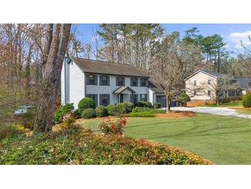 Charming two-story home features a well-manicured lawn and mature trees, creating a serene and inviting atmosphere at 245 Hollyberry Ct, Roswell, GA 30076