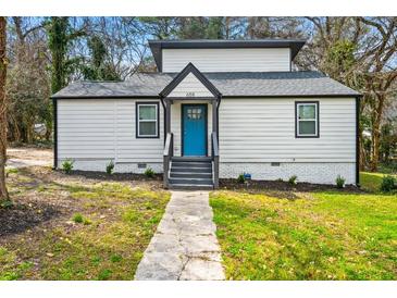 Charming home featuring a new roof, fresh paint, a vibrant blue front door, and a well-manicured lawn at 658 Woods Dr, Atlanta, GA 30318