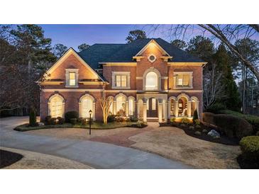 Elegant brick home boasts manicured landscaping, arched windows and stately presence with a circular driveway at 2250 Blackheath Trce, Alpharetta, GA 30005